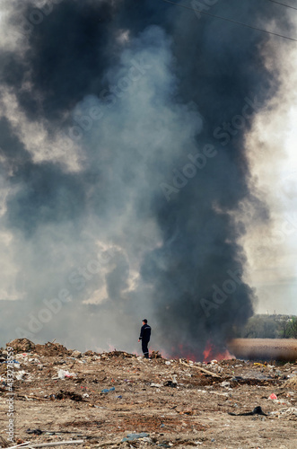 firefighter looks at a large fire and smoke from dry grass