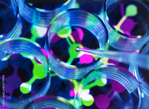 Conceptual image to illustrate biotechnology, Scientist pipetting chemical formula into multi well plate during an experiment