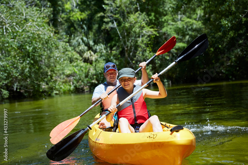 Smiling girl with father canoeing with oar in lake photo