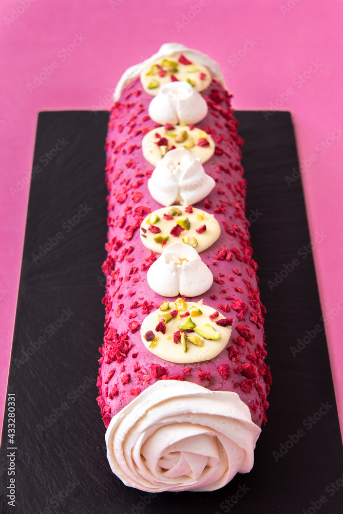 Raspberry Roulade Meringue Dessert on black plate and pink background Raspberry Roulade Meringue Dessert on black plate and pink background