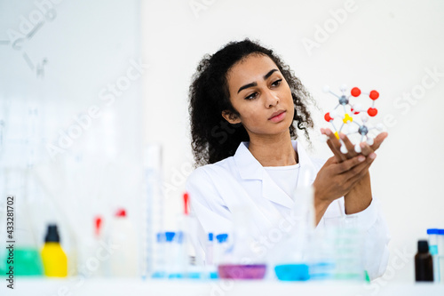 Young female researcher analyzing molecule model in laboratory