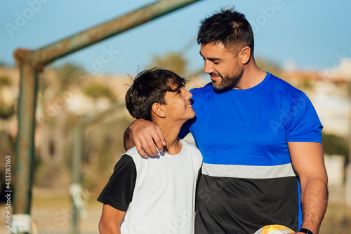 Smiling father with arm around neck of son at sports court photo