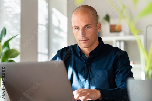 Male freelancer working on laptop in home office