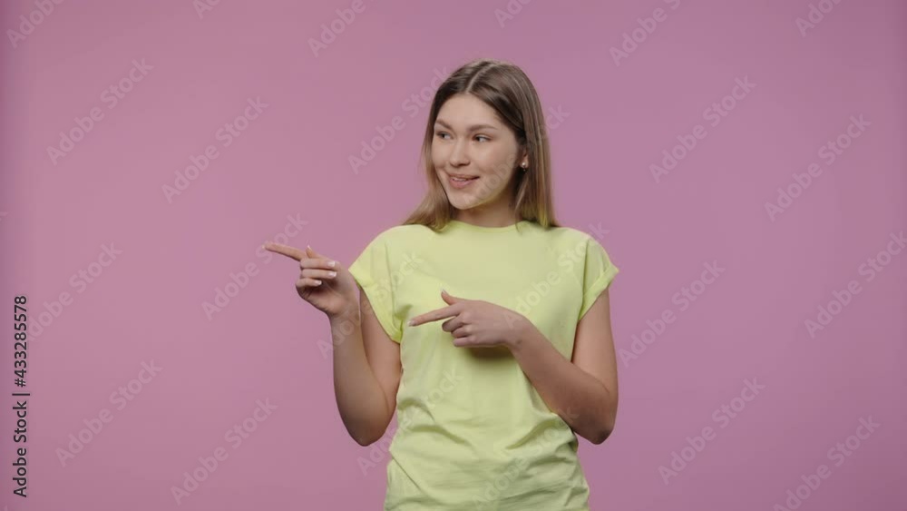 Portrait of model with natural beauty pointing side hand for something, then shows thumb like. Young girl in yellow t-shirt poses on purple studio background. Close up. Slow motion ready 59.94fps. Portrait of model with natural beauty pointing side hand for something, then shows thumb like. Young girl in yellow t-shirt poses on purple studio background. Close up. Slow motion ready 59.94fps.