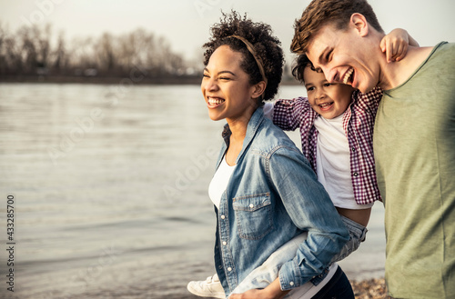 Cheerful family standing by lake during sunset photo