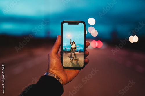 Young man photographing woman on skateboard during dusk photo