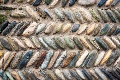 Old stone's wall, with a geometrical texture, composed of stones aligned in a herringbone pattern.