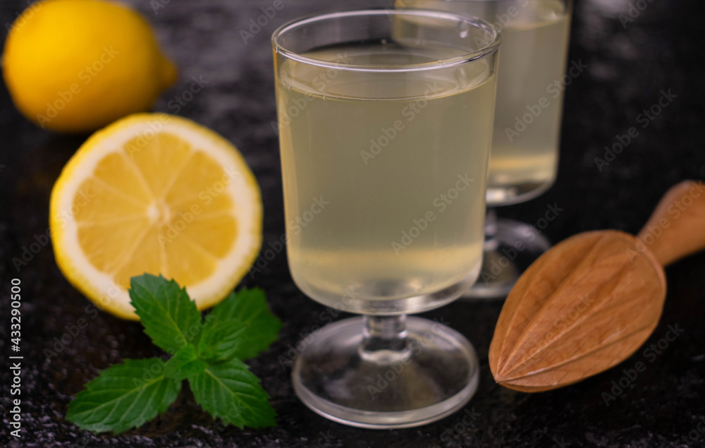 Fototapeta premium Liqueur limoncelo in a glass on a black background. Close-up.