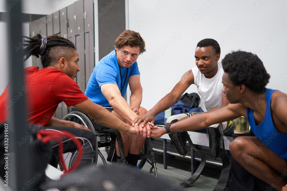 Amputee and wheelchair athletes joining hands in huddle in locker room Amputee and wheelchair athletes joining hands in huddle in locker room