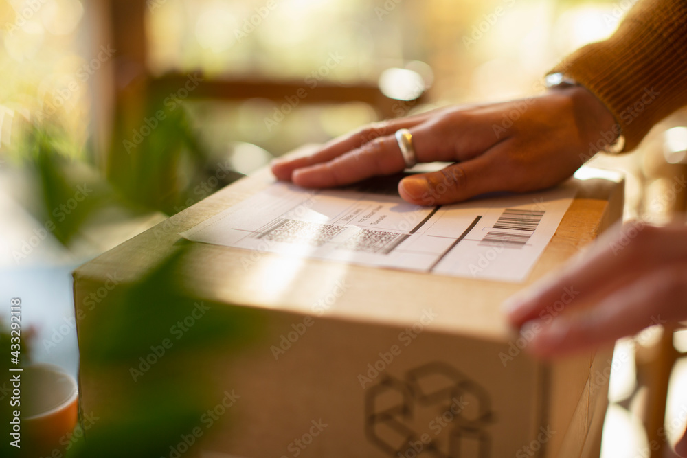 © Martin Barraud/Caia Image - Close up business owner placing shipping label on package