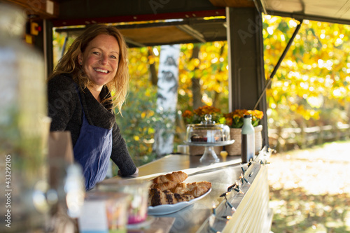 Portrait happy female food cart owner working in park photo