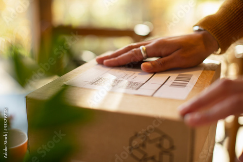Close up business owner placing shipping label on package photo