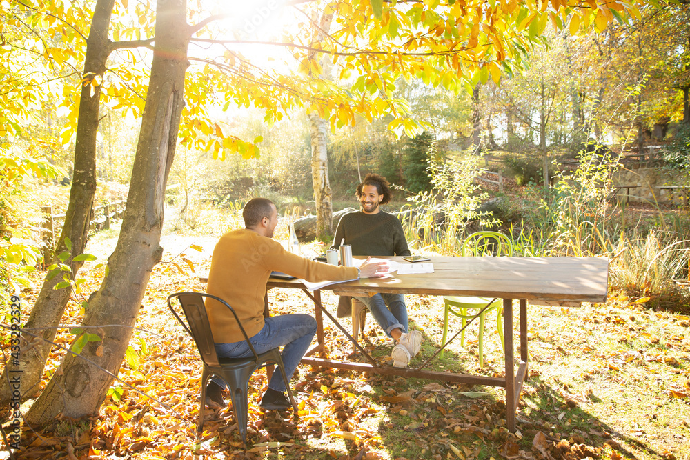 Businessmen meeting at table in sunny idyllic autumn park Businessmen meeting at table in sunny idyllic autumn park