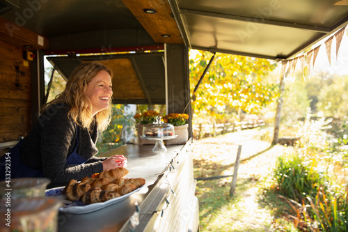Happy female food cart owner in sunny autumn park photo