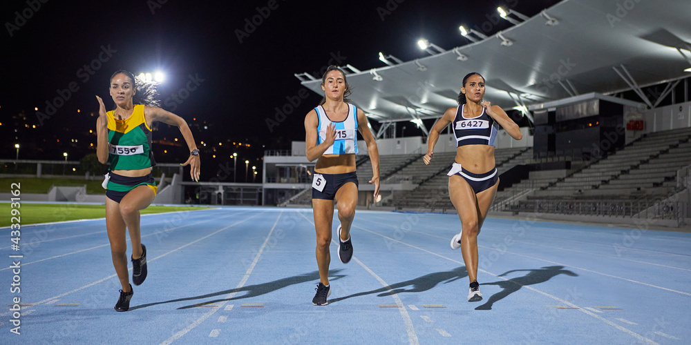 © Trevor Adeline/Caia Image - Female track and field athletes running in competition on night track