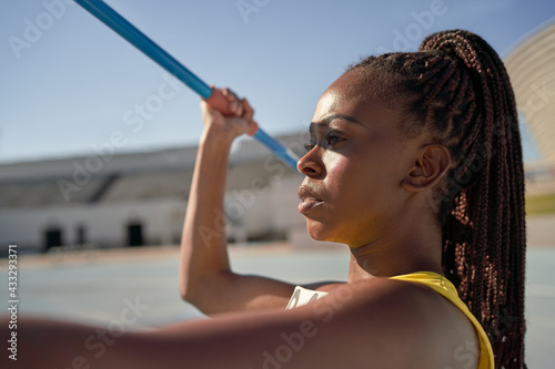 Close up determined female track and field athlete throwing javelin photo