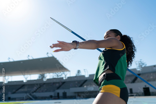 Focused female track and field athlete throwing javelin in stadium