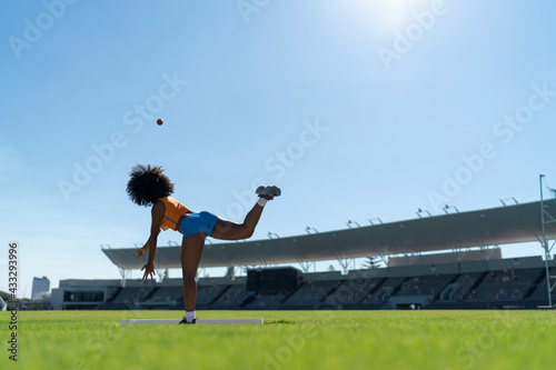 Female track and field athlete throwing shot put in sunny stadium photo