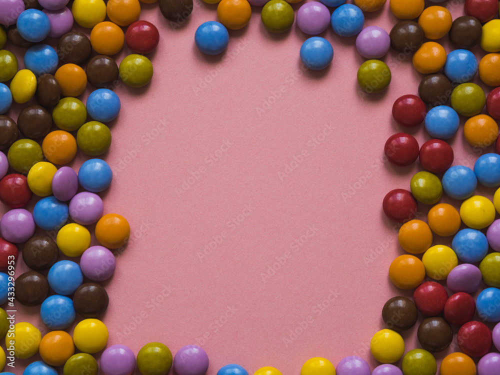 Top view of colorful chocolate candy with a frame in the center. Pink background Top view of colorful chocolate candy with a frame in the center. Pink background