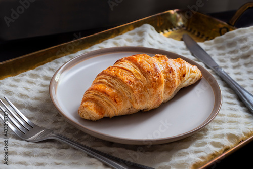 Fresh French croissant with butter served for breakfast on the vintage brass tray. Photography of the delicious croissant with butter, part of food photography collection.