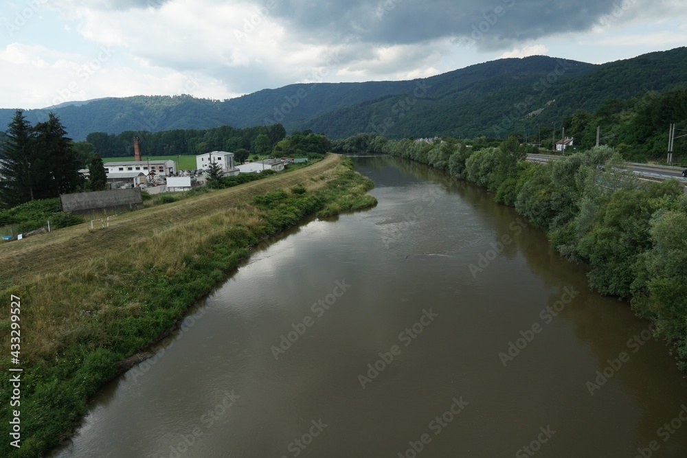 River Hron in Slovakia around town Zarnovica. There is an old industrial zone on the left bank and a highway on the right bank. On the horizon there are hills with coniferous woodland. 
