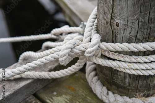 Many ropes tied to a wooden bridge in the harbor. © Jerker