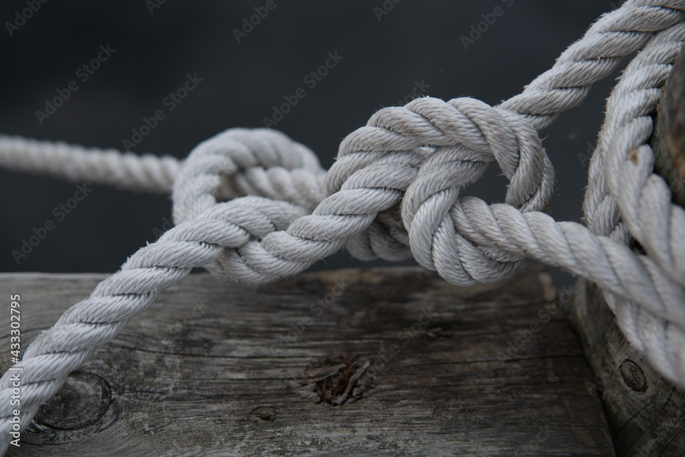 A beautiful tied knot in the harbor. White old rope. Strong maritime team work concept.