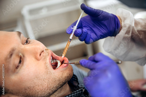 Dentist with syringe making injection with anesthetic for patient during dental procedure