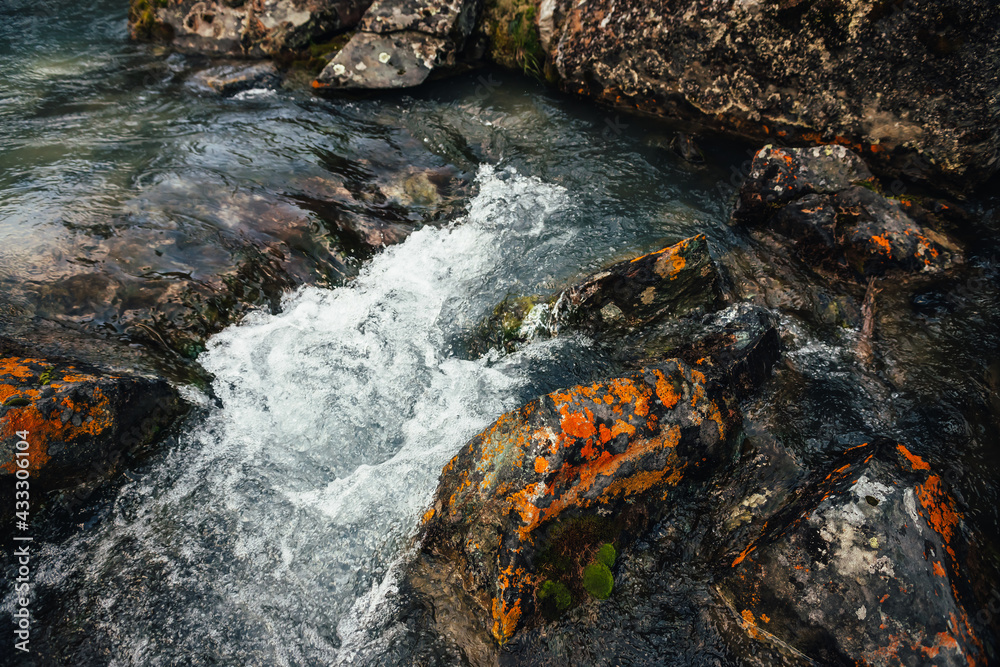 Scenic nature background of turquoise clear water stream among rocks with mosses and lichens. Atmospheric mountain landscape with mossy stones in transparent mountain creek. Beautiful mountain stream. Scenic nature background of turquoise clear water stream among rocks with mosses and lichens. Atmospheric mountain landscape with mossy stones in transparent mountain creek. Beautiful mountain stream.