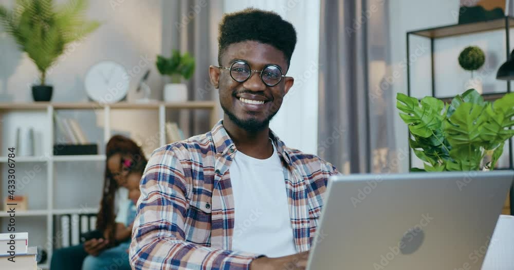 African american guy sitting at table with laptop, smiling and looking ...