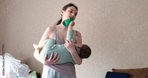 Tired mother holding baby on hands at home. Mom cradles baby son to sleep at home