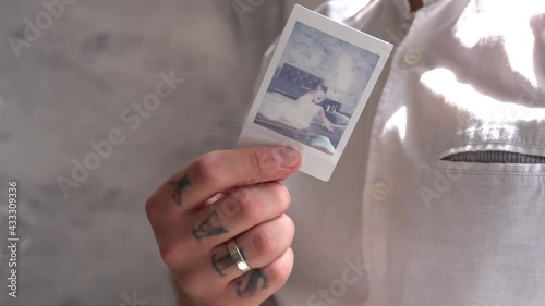 Hand Holding And Shaking The Polaroid Photo To Fastened The Drying Process
