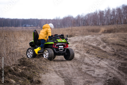 a two-year-old child rides his car on a field in the fall