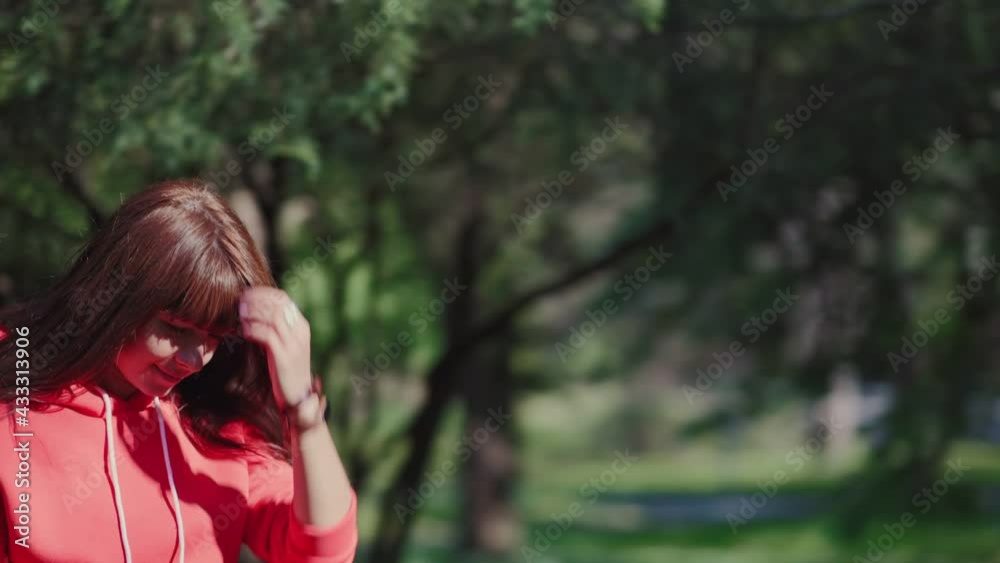 A young woman walks through the park, touching the leaves of the trees with her hand. The sun's rays shine through the trees. Pan shot. A young woman walks through the park, touching the leaves of the trees with her hand. The sun's rays shine through the trees. Pan shot.