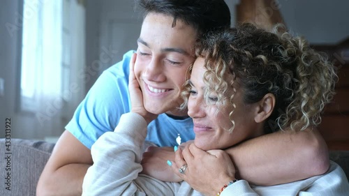 Portrait of middle age mother spend time with teenager son, relatives people hugging at home, adult attentive millennial grateful child wrapped in a plaid or warm sweater loving mommy caring 
