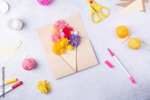 Fototapeta Naklejka Na Ścianę i Meble -  Small child doing a bouquet of flowers out of coloured paper and coloured knitting balls for mom. Simple gift idea. view top, copy space