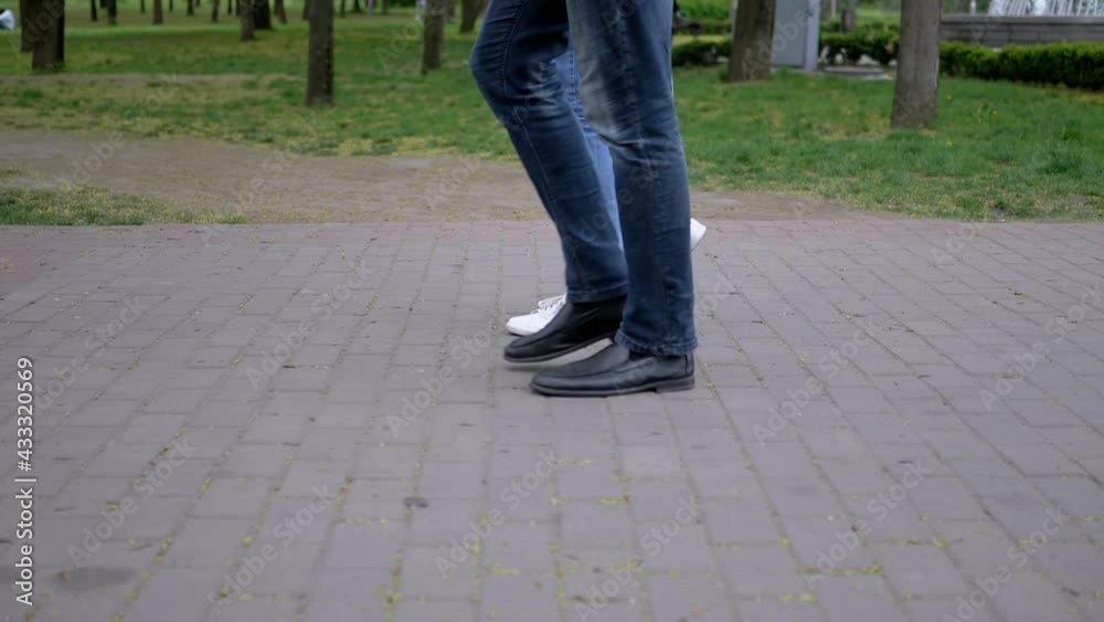 Feet of People, Passers-by Walk on Paving slabs in Park. Slowly Movement of a person along a street. Training of leg muscles in sneakers, boots, shoes. Walking people in the fresh air. Slow motion.