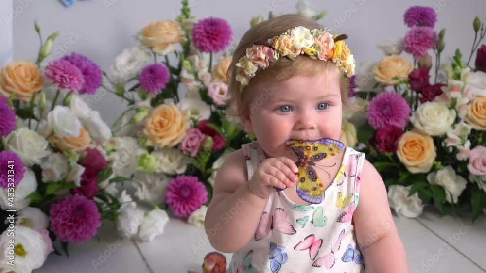 Slow Motion a little cute baby in dress sitting on the flowers background Slow Motion a little cute baby in dress sitting on the flowers background