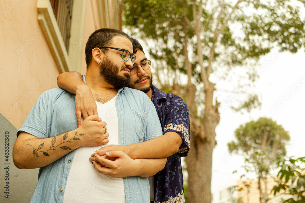 Pareja de novios gay latinos con barba abrazados en la calle con manos  entrelazadas foto de Stock | Adobe Stock