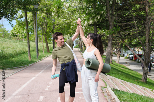 Young sport couple slapping hands in a 'high-five' and laughing. Fitness outside.
