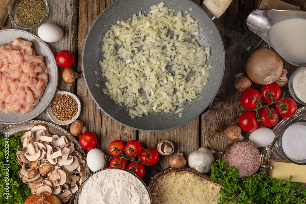 Fototapeta premium Risotto with mushrooms. Cooking process. On a wooden table, ingredients: tomatoes, eggs, rice, mushrooms, herbs, spices. Bright, contrasting colors. Daylight, top view, close-up