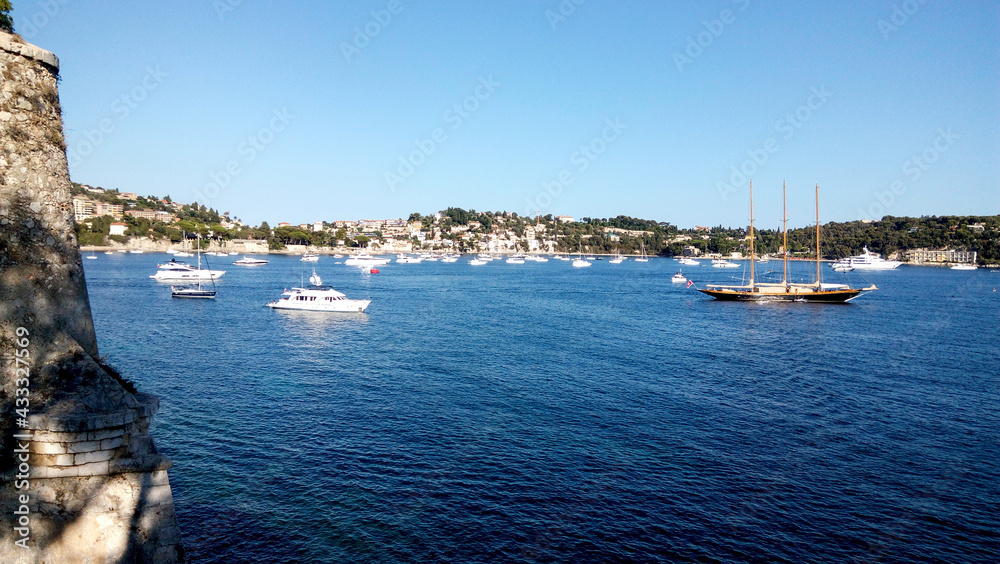 Beautiful top view of the shoreline with tourists  relaxing in Villefranche-sur-mer on a sunny day. Wonderful trip to the Cote d'Azur in France. Scenic seaside of the sea country town. Cap Ferrat view