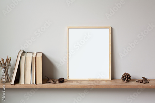 11x14 thin wood vertical frame mockup for art and quotes, sitting on a wooden shelf. Vintage stack of books, autumn leaves, pine cones and a glass jar of pencils as props.