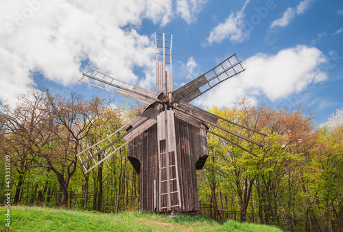 Antique wooden windmill on a hill near the forest. Autumn rural landscape