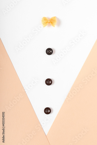 Buttons and a piece of pasta on a pastel white and beige background as a shirt and suit coat. Minimal flat lay concept.