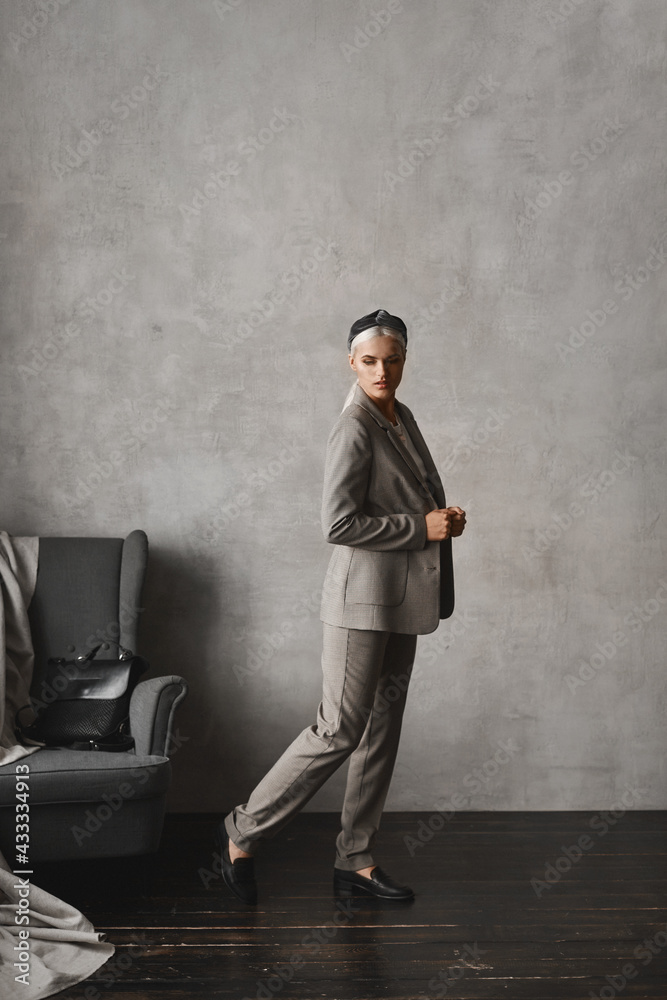 Young stylish business lady in a modish suit posing in an empty interior of the vintage apartment