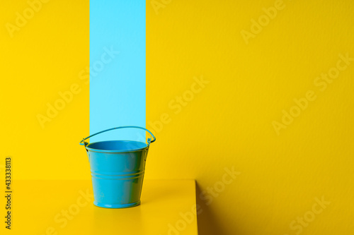 paint service concept. blue bucket over yellow background. design and decor conceptual photo