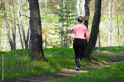 Sports activities in nature. Young girl runs through the spring forest, healthy lifestyle