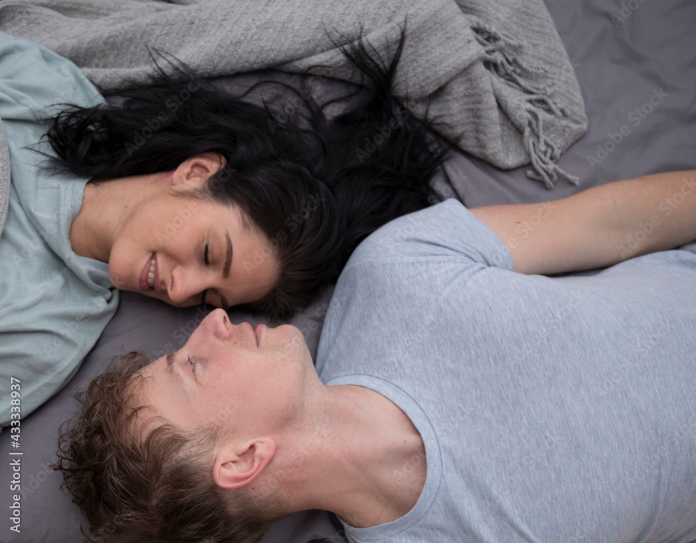 High angle view of smiling couple relaxing and lying down in bed .They are looking at each other
