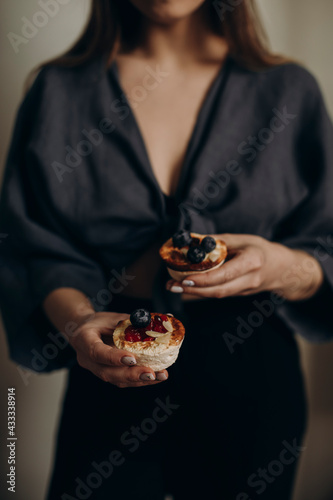 young woman holding curd muffins in her hands. a healthy dessert in the hands of a beautiful girl. holding muffins dessert with blueberries and cranberries.